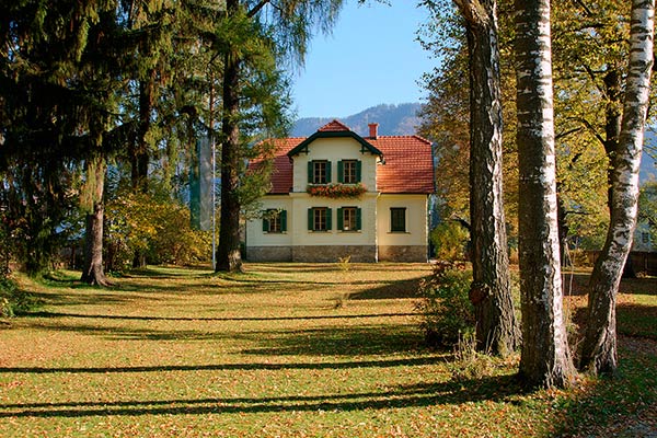 Auf dem Bild ist das Roseggermuseum im Herbst zu sehen - links und rechts sind große Bäume als Allee.